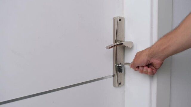 The man opens the door of the room with the key.