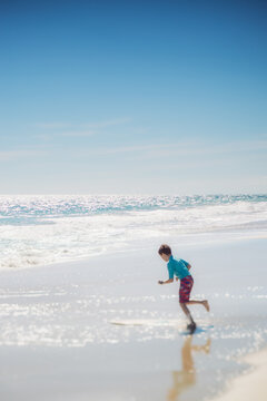 Boy running with a skim board at the beach