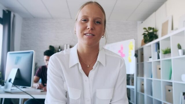 Video of beautiful blonde business woman looking and speaking through the webcam while making a video conference from the office.
