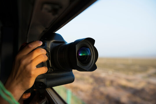 Man holding camera taking photo outward from train