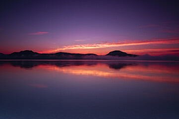夜明けの空を湖面に映す湖。屈斜路湖、北海道。