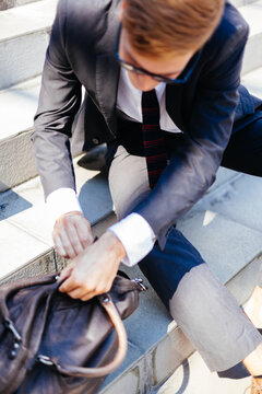 Stylish Businessman Opening His Briefcase Sitting on the Stairs