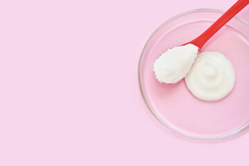 Collagen white powder. Pastel color background. Health product. Woman cosmetics concept. Sport supplement. Skincare cosmetics. Pink monochrome. Cream smear. Spoon