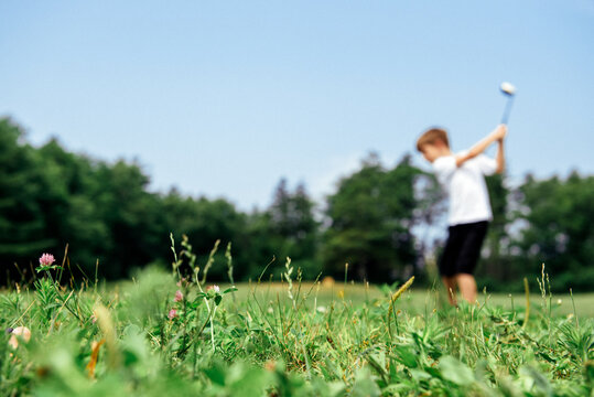 Young boy practices his golf swing at a driving range