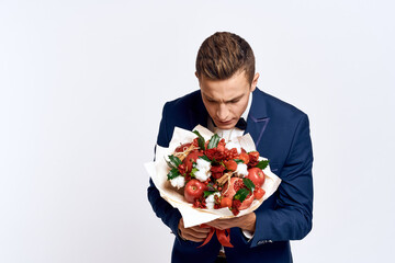 An elegant man in a classic suit with a bow tie holds a bouquet of flowers in his hand 