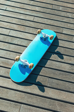 Overhead of blue skateboard on wooden floor.
