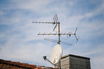 Satellite dish and terrestrial antenna on the roof against the sky
