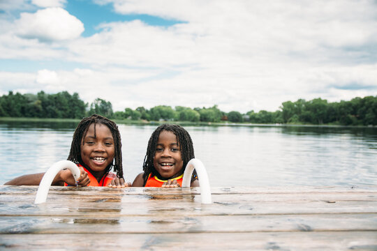 Two Smiling African American Girls By a Dock In A Lake