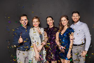 celebration, people and holidays concept - happy friends at party under golden confetti over black...