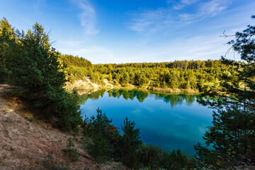 Fototapeta na wymiar Beauty of nature in the countryside. Rural landscape. Forest around blue lake. Reflections on water surface