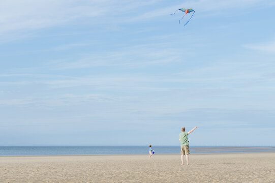Father and son flying a kite on the beach