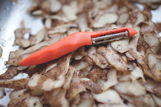close up of vegetable peeler on a pile of potato skins
