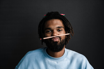 Young funny businessman making mustache with pencil