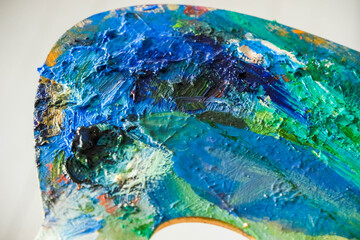 Art palette close up texture with oil paint strokes and paint can. Artist equipment - colorful palette with multiple colors oil paint on it.