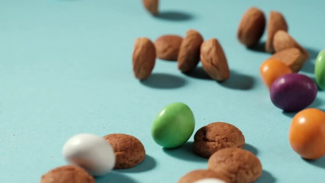 Scattered traditional dutch cookies kruidnoten gingersnap over blue background. St Nicholas day Sinterklaas in December, children holiday in Netherlands and Belgium. Full HD video, 100 fps slow motion