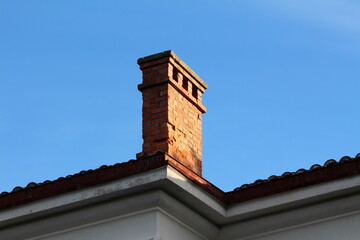 Old leaning cracked red bricks chimney with three openings mounted on side of abandoned office...