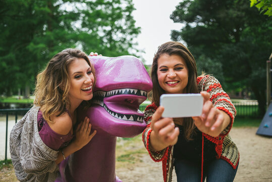 Young female friends taking a selfie with a T-Rex in the park
