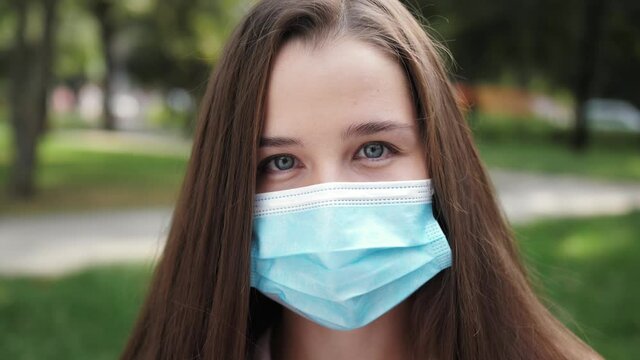 Portrait of a woman about in the city streets during the day, wearing a protective virus face mask against air pollution and Coronavirus Covid 19, Girl looking at camera and smiling.