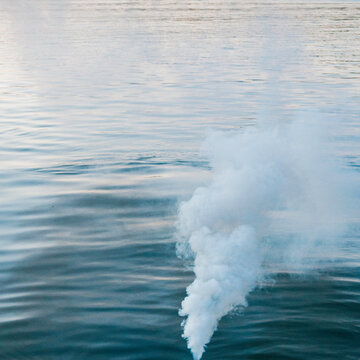 billowing white smoke over a lake