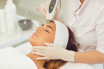 Woman receiving ultrasound apparatus facial cleaning in beauty salon