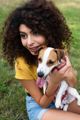 Selective focus of young woman holding dog and looking away