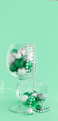 Christmas baubles in a wine glass on a light green background