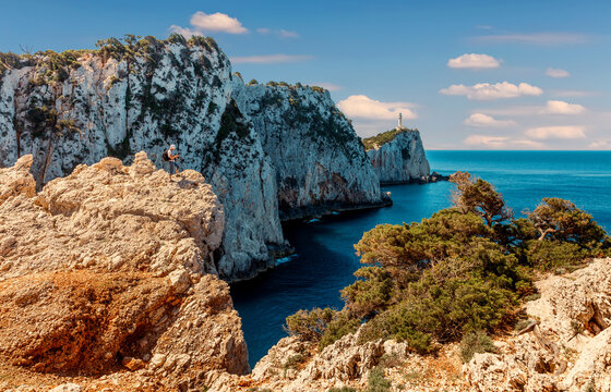 Beaotiful View of the Lighthouse on the cliff. sunny seascape of Cape Lefkatas with old lighthouse in summer day. Wonderful picturesque vivid landscape over the Ionian Sea. Lefkada island. Greece.