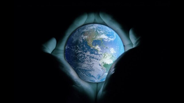 3d animation: The planet earth with a blue glow revolves around its axis on a black background. Gradually appears men's hands that support our world. The concept of humanity's fragility.
