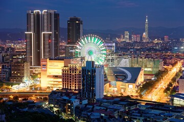 Aerial panorama of busy Taipei City, the capital of Taiwan on a romantic evening in blue twilight with a Ferris wheel in Dazhi Commercial District and Taipei 101 Tower among skyscrapers in downtown