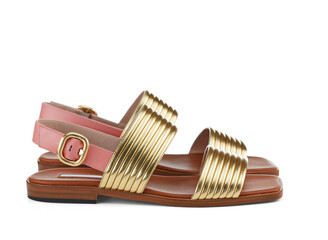 Beautiful elegant open summer sandals in gold and pink leather with low heels, isolated on a white background with shadow. Summer shoes for walking around the city. Side view.