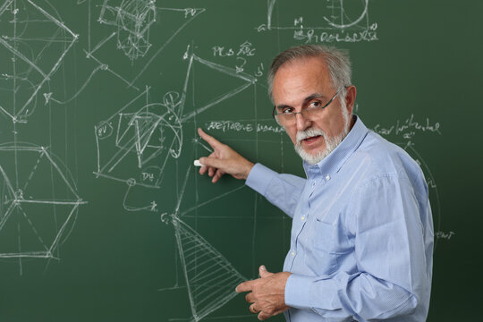 Mature professor teaching in front of the blackboard