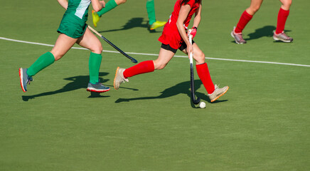 Three women battle for control of ball during field hockey game. Team sport concept.