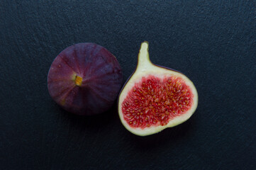 Two figs on black background. Whole figs and one fig sliced. Autumn dish. Fresh figs. Autumn harvest. Free space for text.