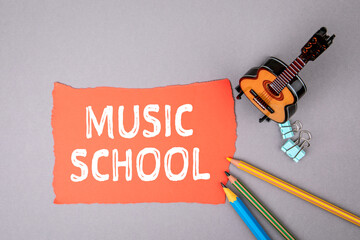 MUSIC SCHOOL. Miniature guitar and colored pencils on table