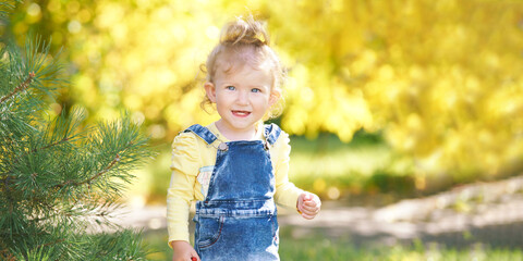 Beautiful little girl smiling. Look not at the camera. Park outside the house. Advertising photo. Positive child after quarantine. End lockdown. Horizontal banner. Copyspace