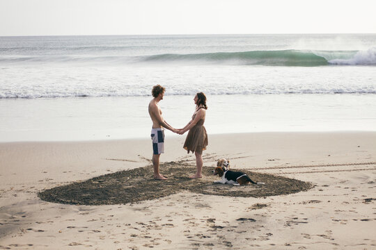 Love couple standing in a heart drawn on the beach
