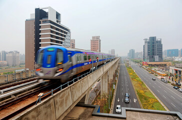 Plakat Scenic view of a metro train traveling on elevated rails of Taoyuan Mass Rapid Transit System (Taoyuan International Airport MRT System) under cloudy sky in Chunli, New Taipei City, Taiwan