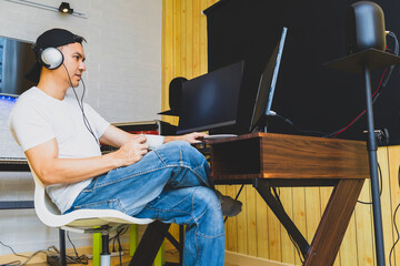 asian young man enjoy coffee while listening music and watching video on  social media