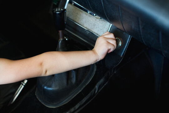 A little girl plays with knobs inside a convertible car