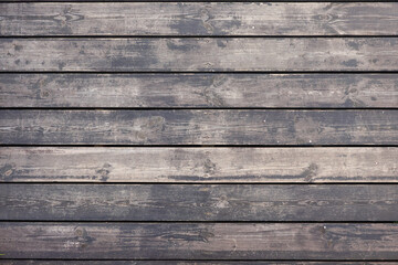 A fragment of a wooden flooring of a street footpath made of planks. The dark paint has worn off,...