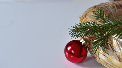 Strohkranz mit Fichtenreisig, Christbaumkugel vor weißem Hintergrund für Weihnachtsbotschaft, weiß, rot, grün, weihnachtliche Farben für Advent