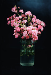 Floral background. Wild roses in a glass jar over stone background. Still Life Flowers. Nature.