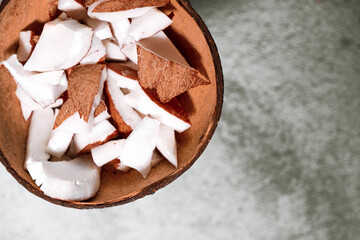 A bowl of coconut pieces on concrete background. Coconut ingredient on plate. Vegan organic snack...