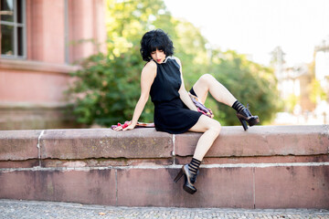 Junge Frau postet im schwarzen Kleid  im Freien 