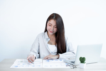 Asian female accountant sits at their desks and calculates financial graphs showing results about their investments, plan a successful business growth process