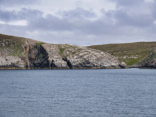 Fototapeta na wymiar Sea cliffs showing rock strata on Whale Firth at the Lee of Vollister on Yell, Shetland, Scotland, UK - this rock is of the Yell Sound 'division' - Psammite, Gneissose. Metamorphic Bedrock.