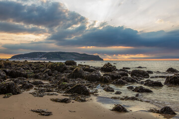 Rocky beach at Llandudno, North Wales. View of the Great Orme with a warm sunset.