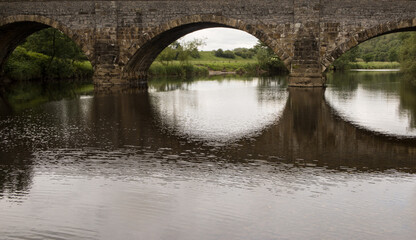 Fototapeta na wymiar Brungerley bridge, Clitheroe. Large stone bridge over the river Ribble with reflections in the water