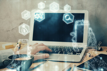 Technology theme hologram with man working on computer on background. High tech concept. Multi exposure.