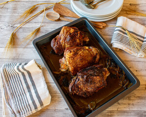 roasted turkey thighs on a baking tray on wooden background